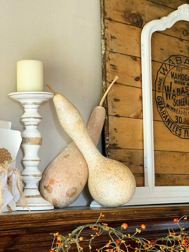 gourds, white candle and books on mantel