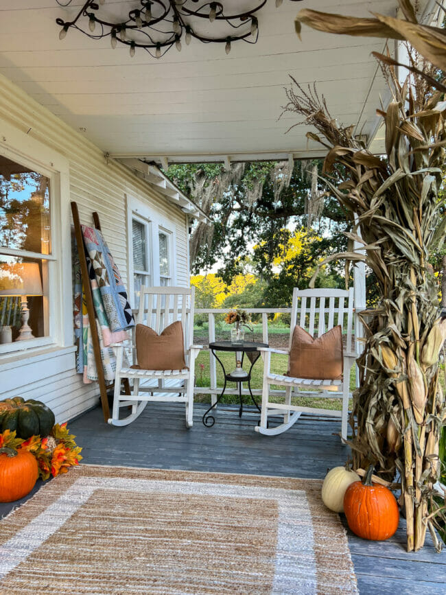 porch with corn stalks, rocking chairs with pillow and pumpkins