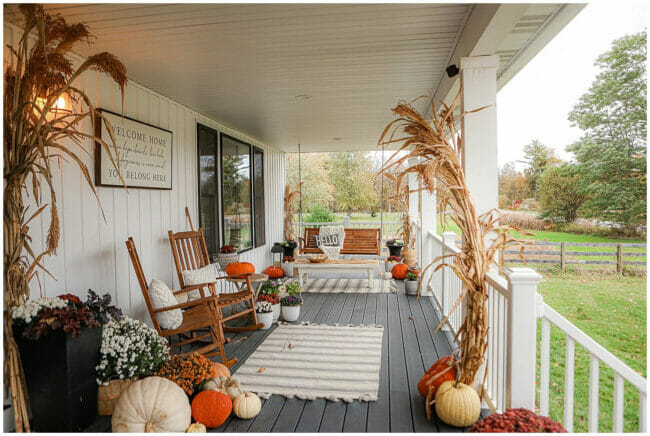 front porch with corn stalks, rugs, rocking chairs, pumpkins and mums