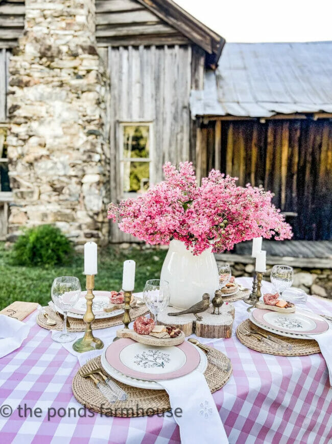 pink and white tablescape with pink flowers, birds, candles and pink plates