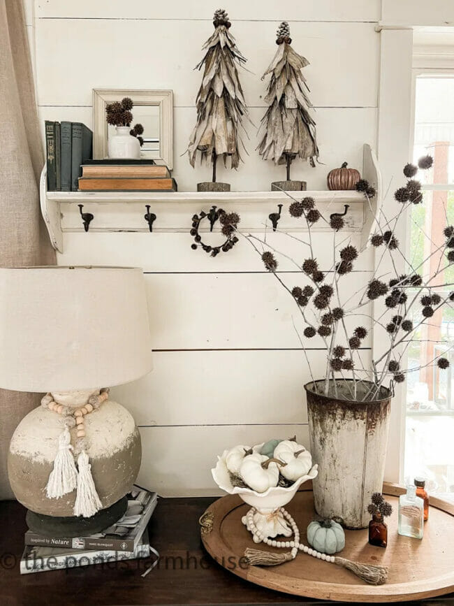 famhouse decor with lamp, shiplap wall, cornstalk trees and stems in a vase