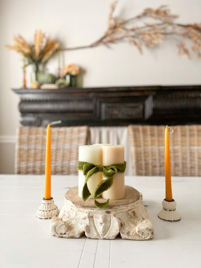 candles on pedestal sitting on table in front of black mantel