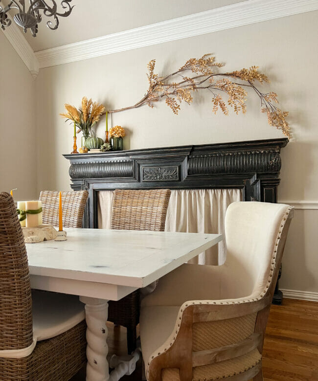 black mantel with branch hanging over and white table with gold candles as centerpiece