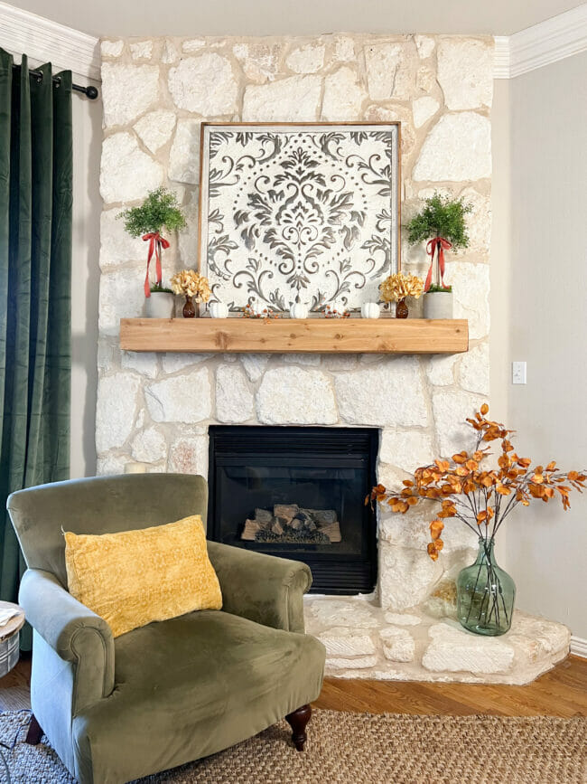 stone fireplace with green chair and fall stems