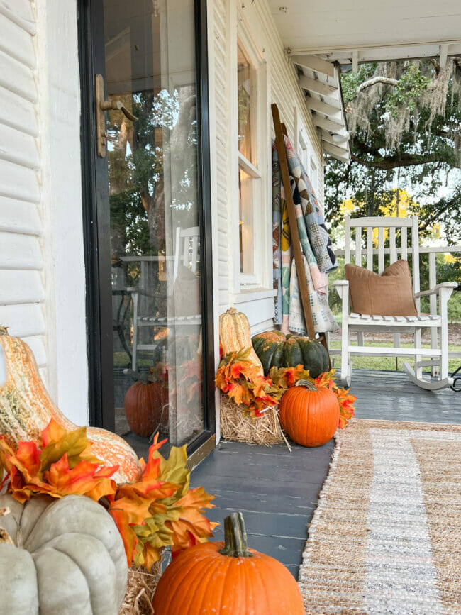 two pumpkin vignettes next to black front door on a fall porch