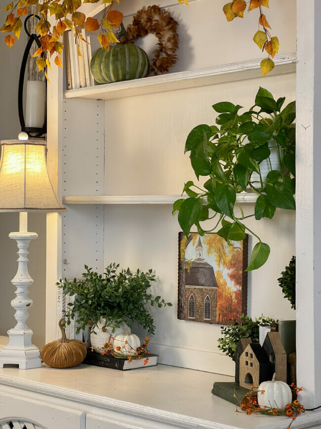 hutch shelves with fall decor, plants and lamp