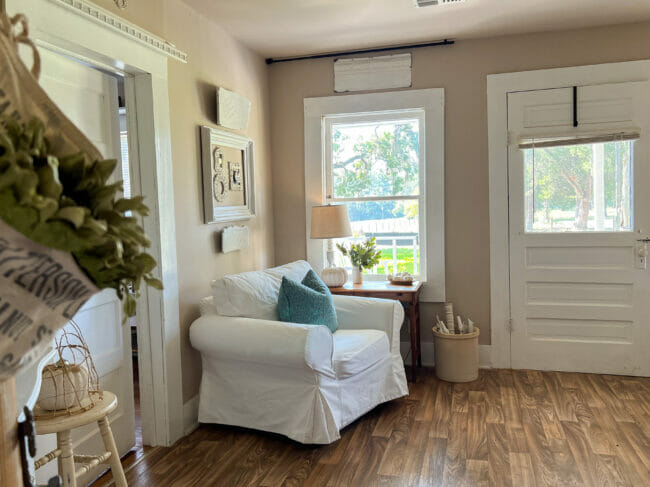 white chair with teal pillow, window and pumpkins