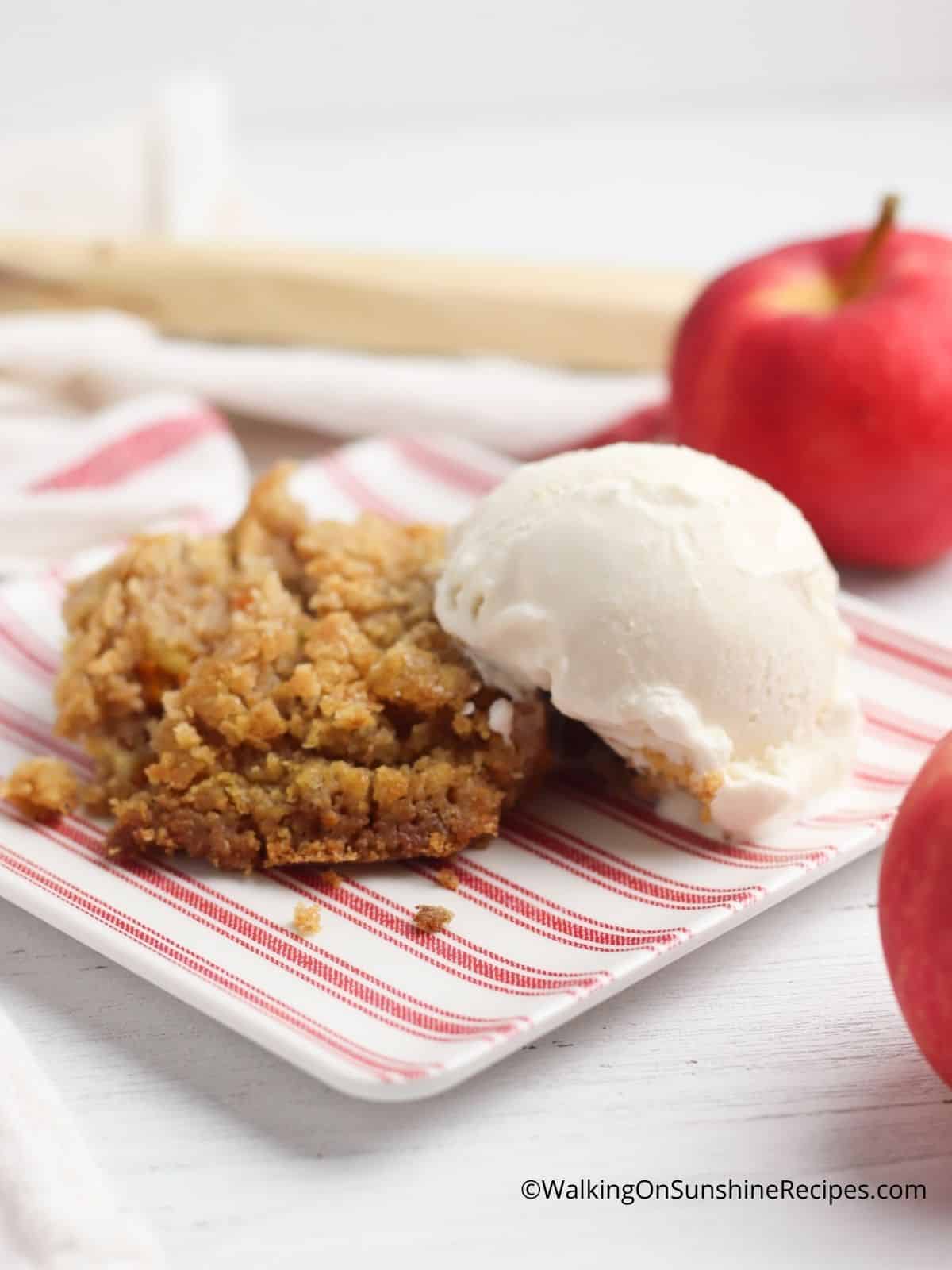 dump cake with apple and scoop of vanilla ice cream on red striped plate