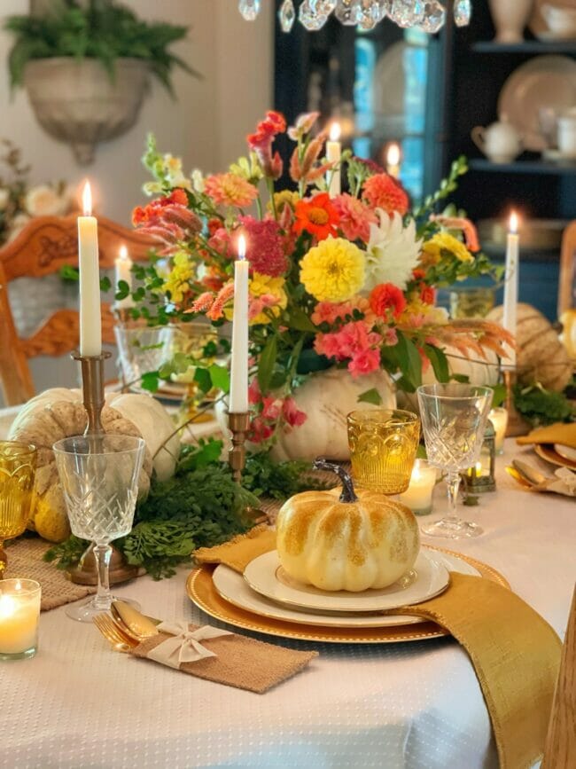 pink and yellow flowers with candles and place setting with pumpkin on top
