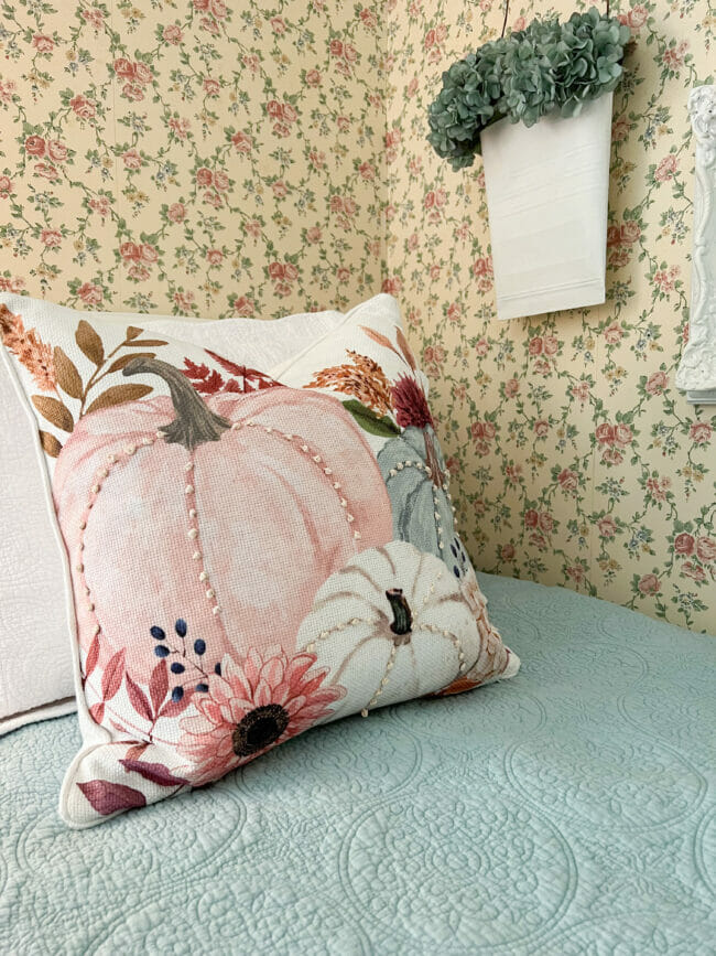 pink pumpkin pillow sitting on bed with blue bedding