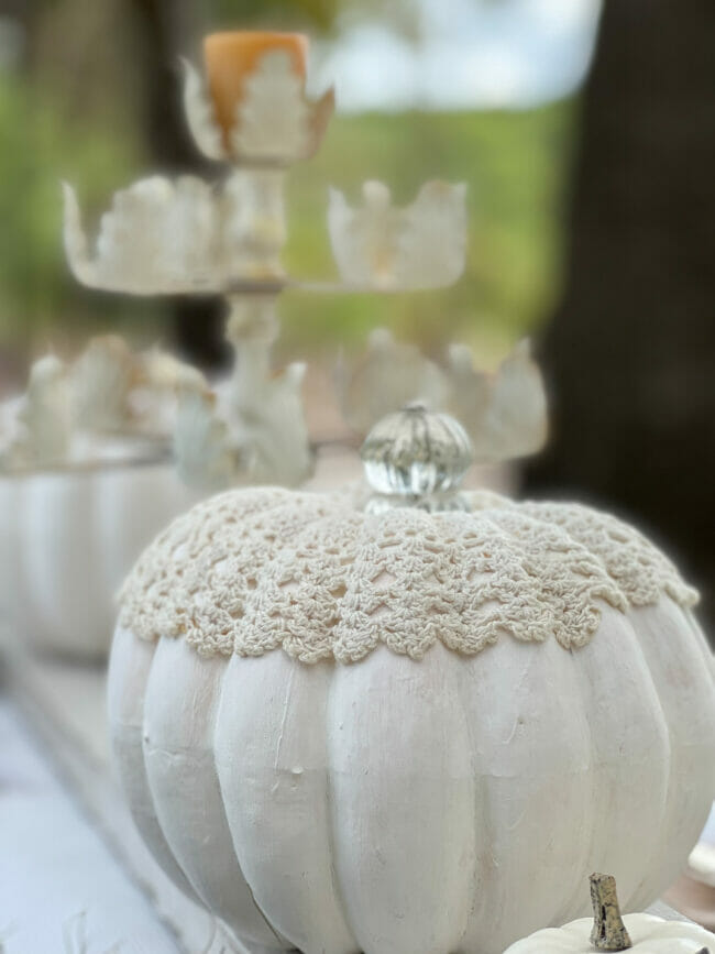 close up of white pumpkin with doily and knob