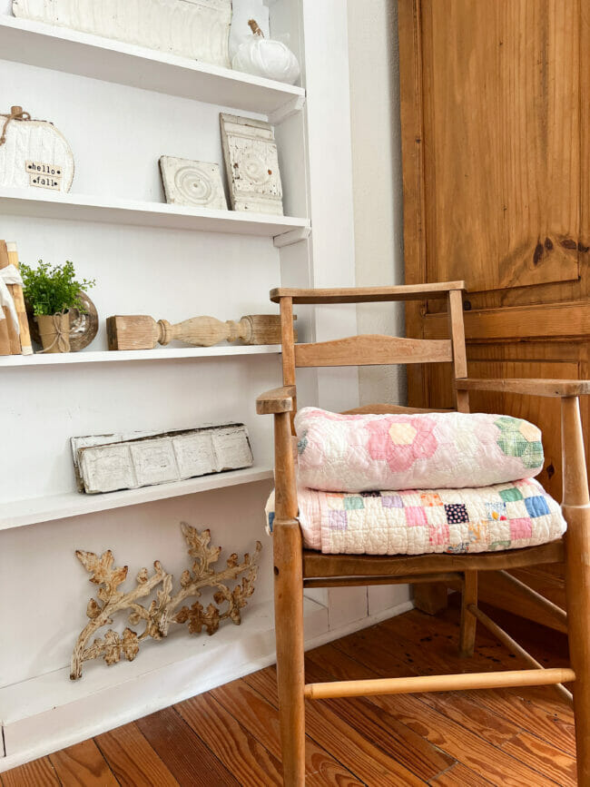 vintage quilts folded in old chair in front of book case