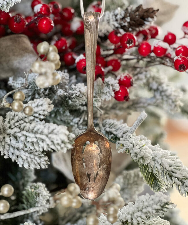 Large vintage silver spoon hanging on flocked tree with red berries