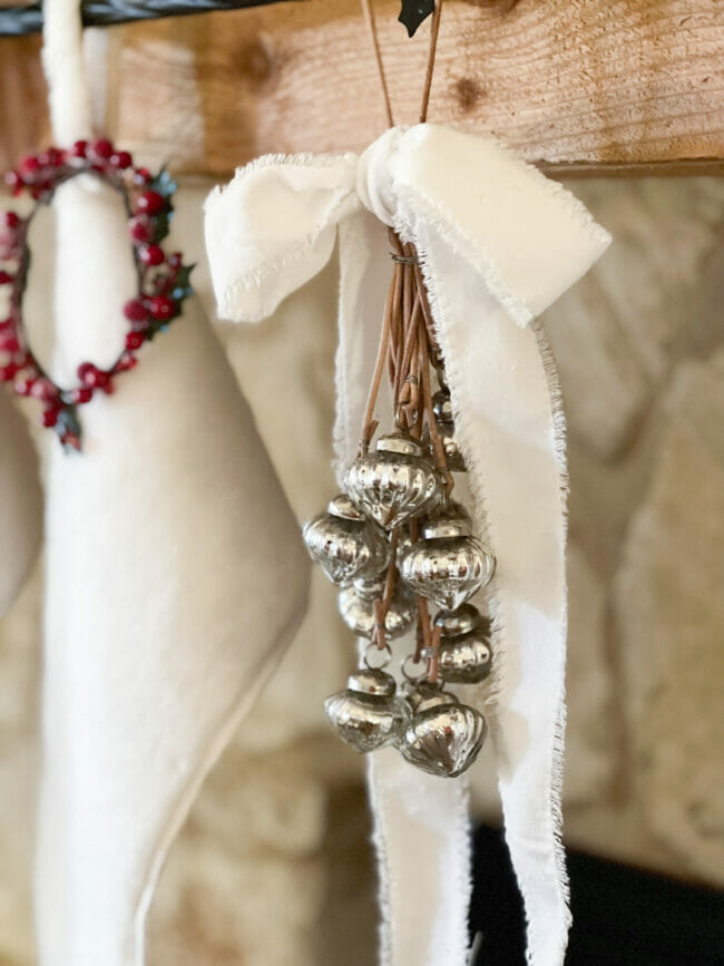 small silver ornaments hanging on mantel with white now and stocking