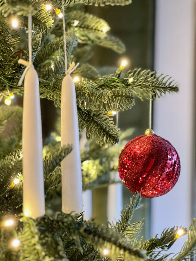 white candles hanging on Christmas tree with red ball ornament