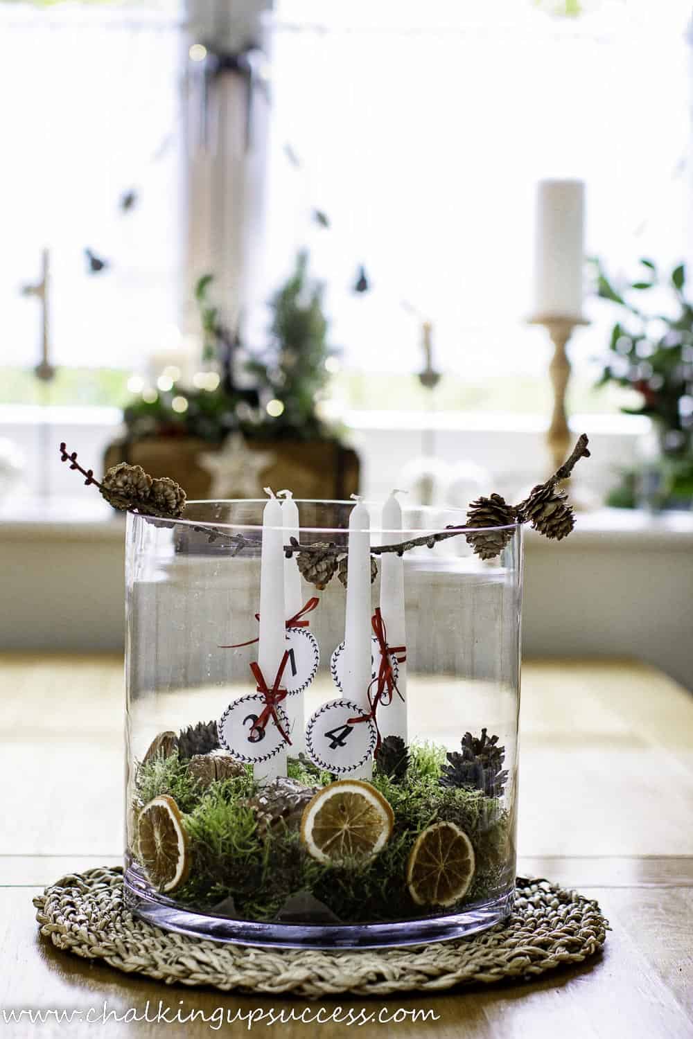 glass jar with greenery, oranges and white candles for Advent