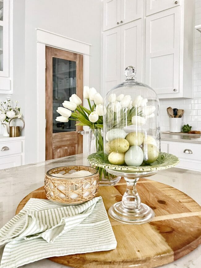 eggs under cloche on wood board in kitchen