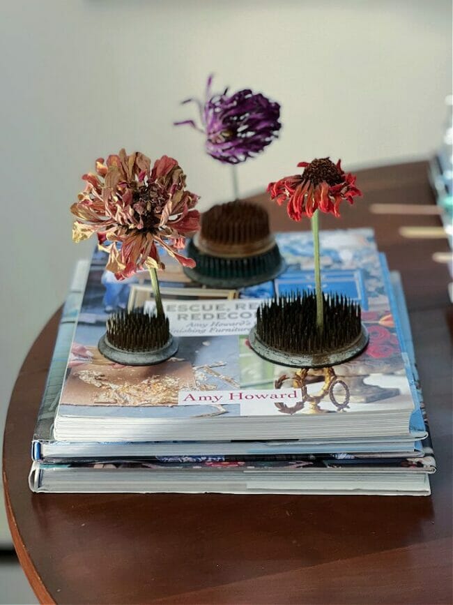 flower frogs with flowers sitting on top of books
