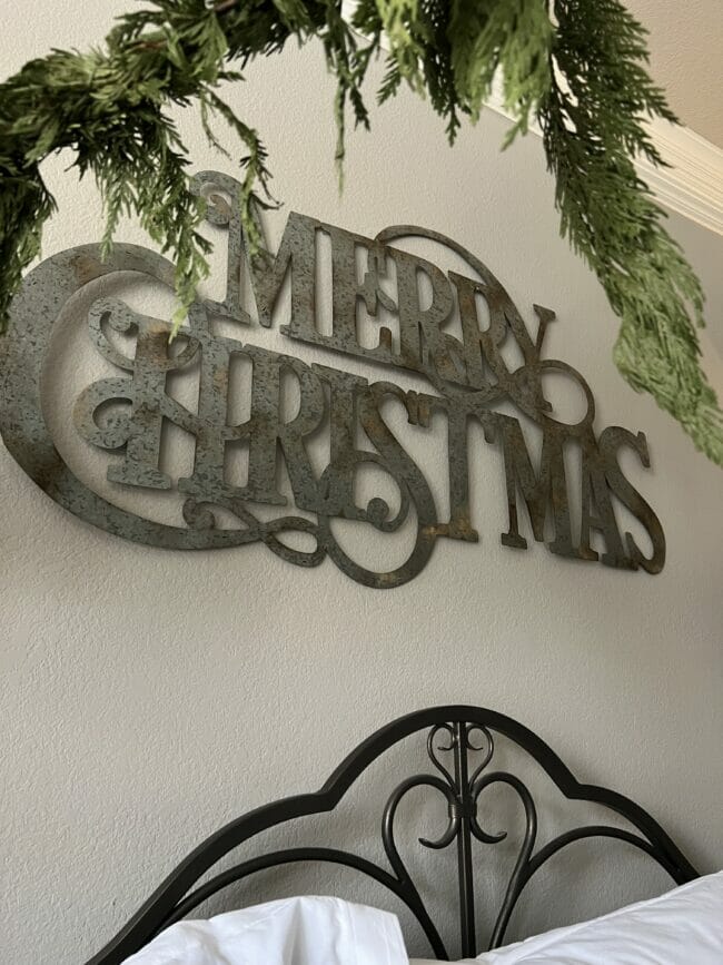 large metal Merry Christmas sign over bed
