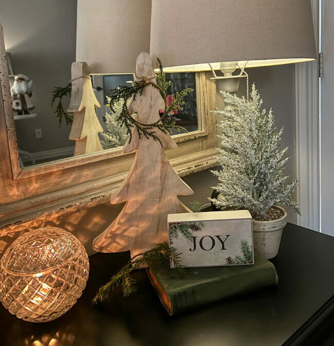 bedside table with candle in glass bowl, trees and a Joy sign