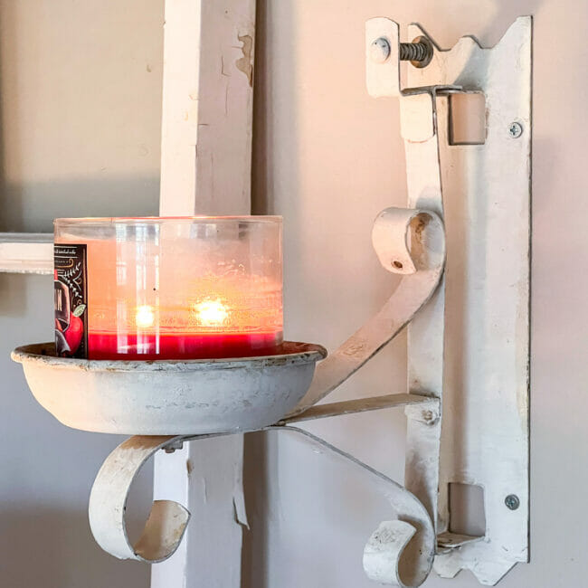 white candle holder on wall with red lit candle