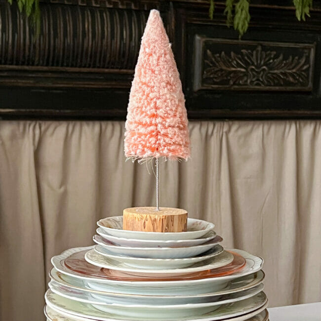 stacked vintage plates with pink bottle brush tree sitting on top