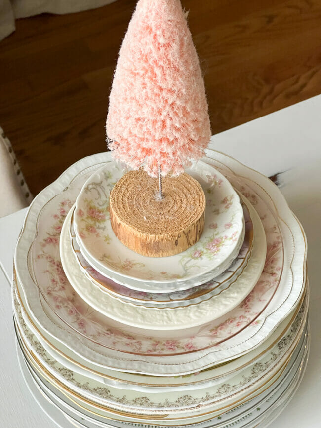 stacked vintage plates with pink bottle brush tree sitting on top