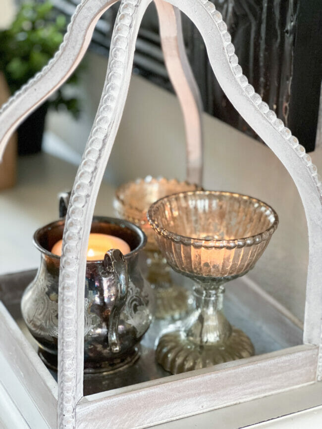 3 silver containers with candles inside white lantern