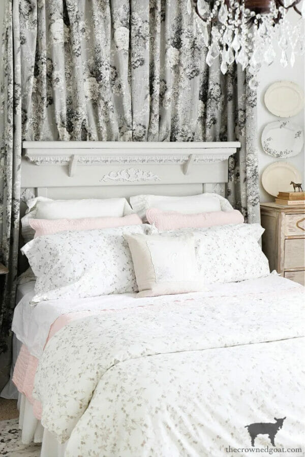 bed with floral sheets and floral curtain behind bed