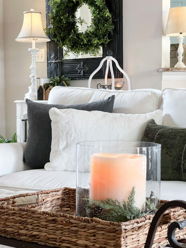 candle on table with white and green pillows in background on white sofa