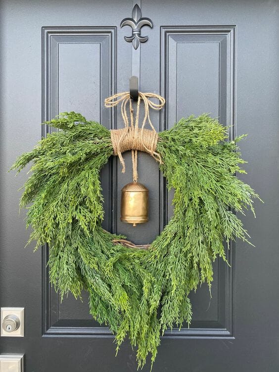green wreath with gold bell on black door