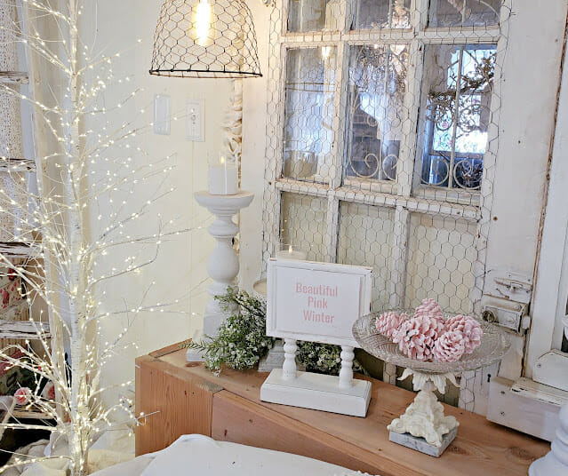 white sign, pink pinecones and twinkly light tree