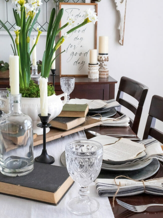 table setting with books, candles and plant in center