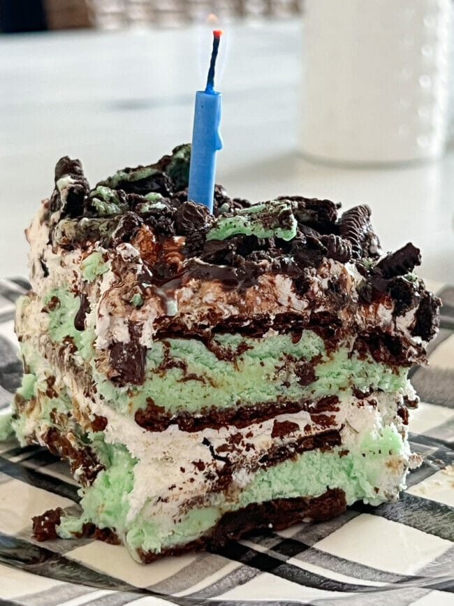 close up of layered mint chocolate ice cream sandwich cake with blue candle