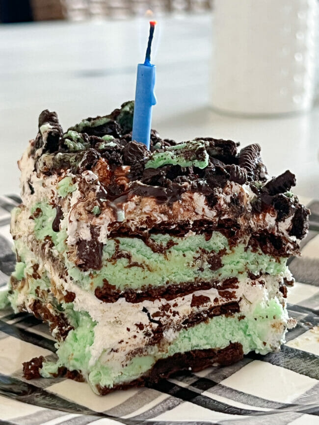 close up of layered mint chocolate ice cream sandwich cake with blue candle