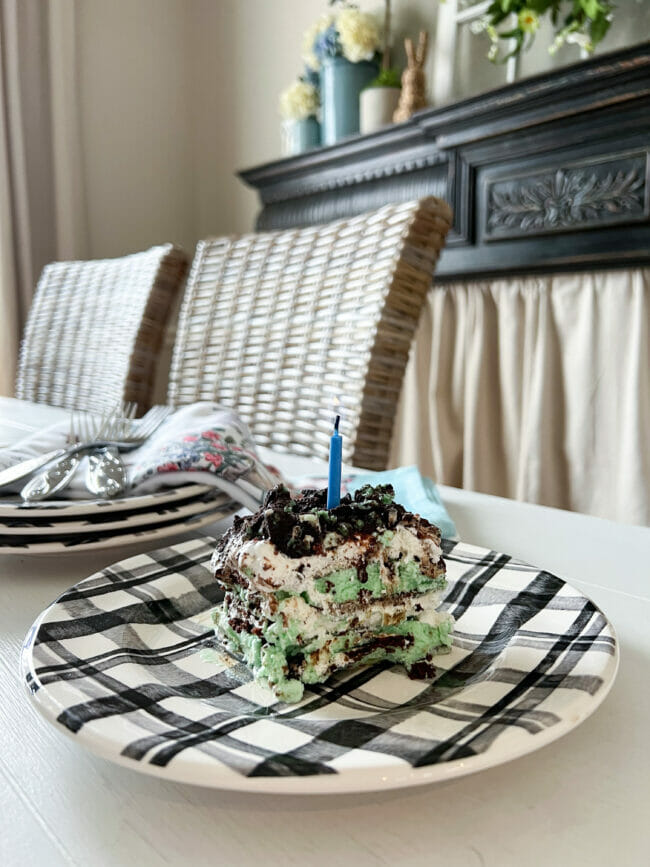 black and white plaid plate with mint chocolate ice cream cake and blue candle on top