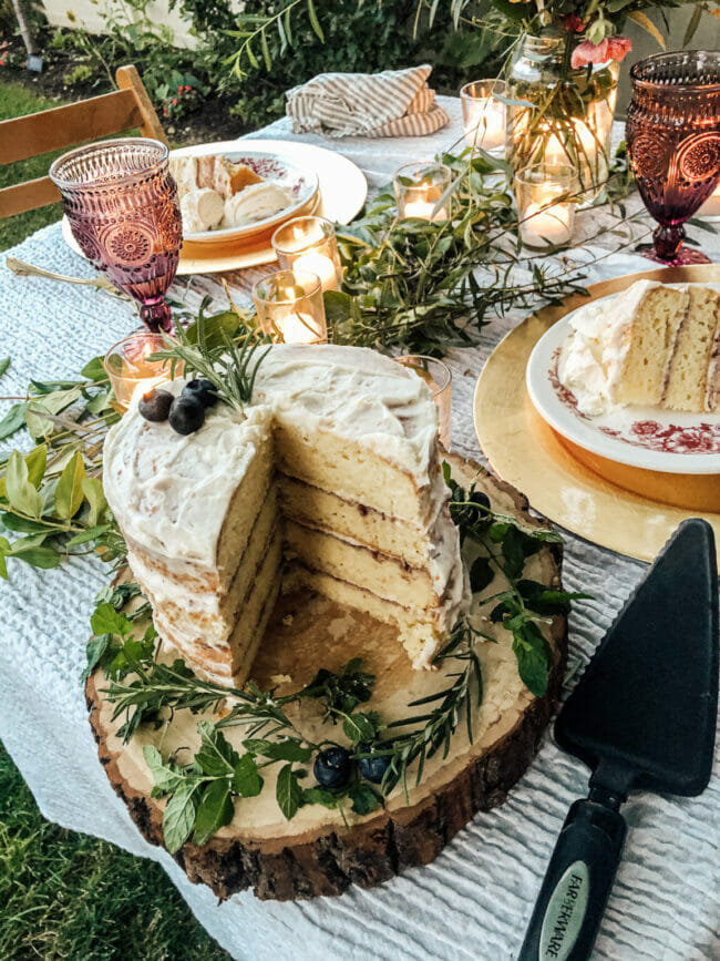 layered cake on table with lots of greenery and candles as a centerpiece