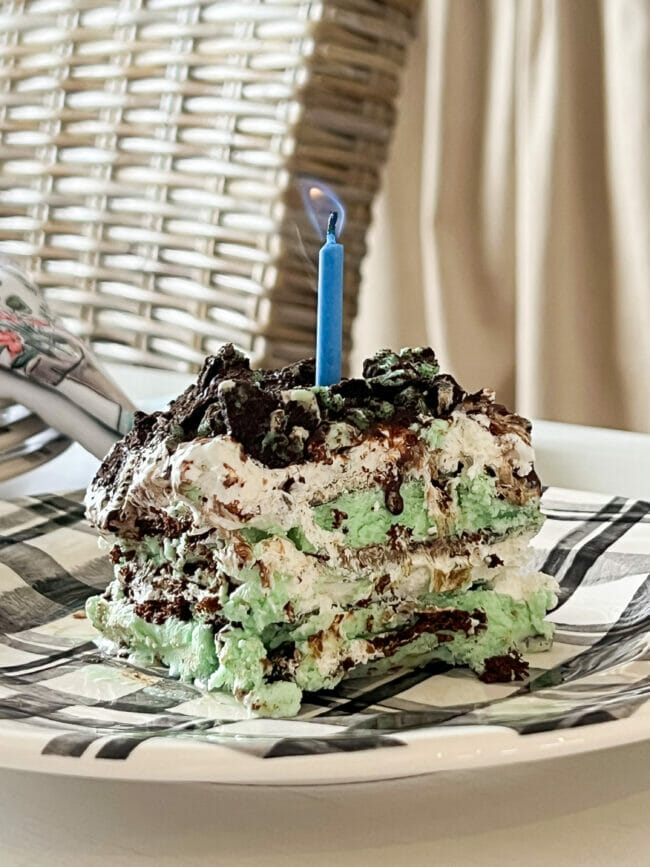 mint ice cream sandwich cake with blue candle on plaid plate