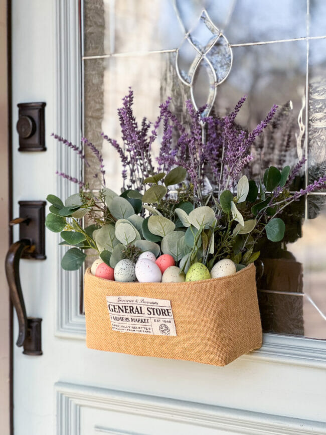 burlap basket hanging on door with eggs and faux lavender