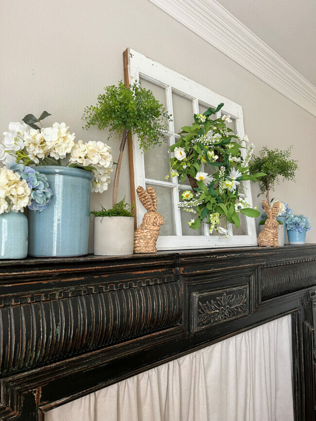 black mantel with blue crocks, straw bunnies and flowers