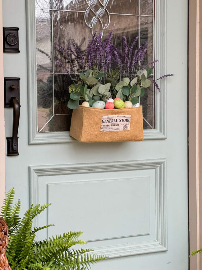 bottom of green front door with burlap basket with eggs