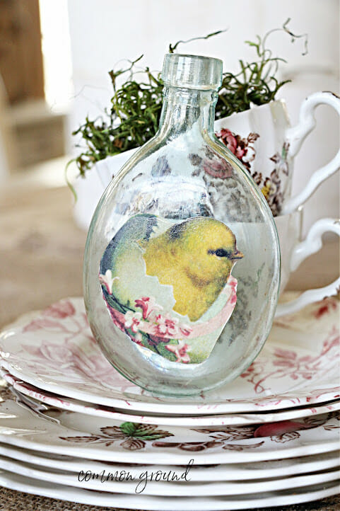 glass bottle with chick stamped sitting on stack of plates