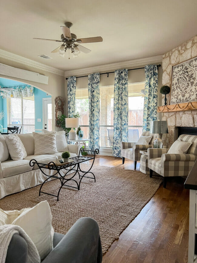 living room with blue curtains, white sofa and gray checked chairs