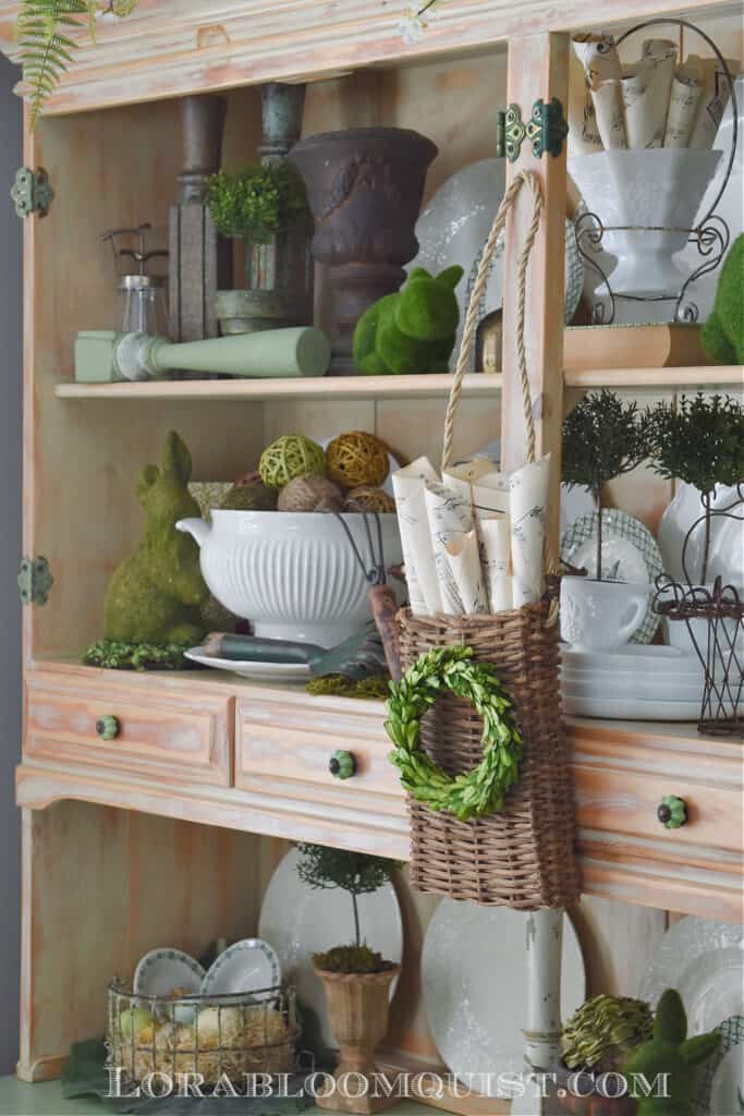 hutch with vintage plates, basket with wreath and green accessories