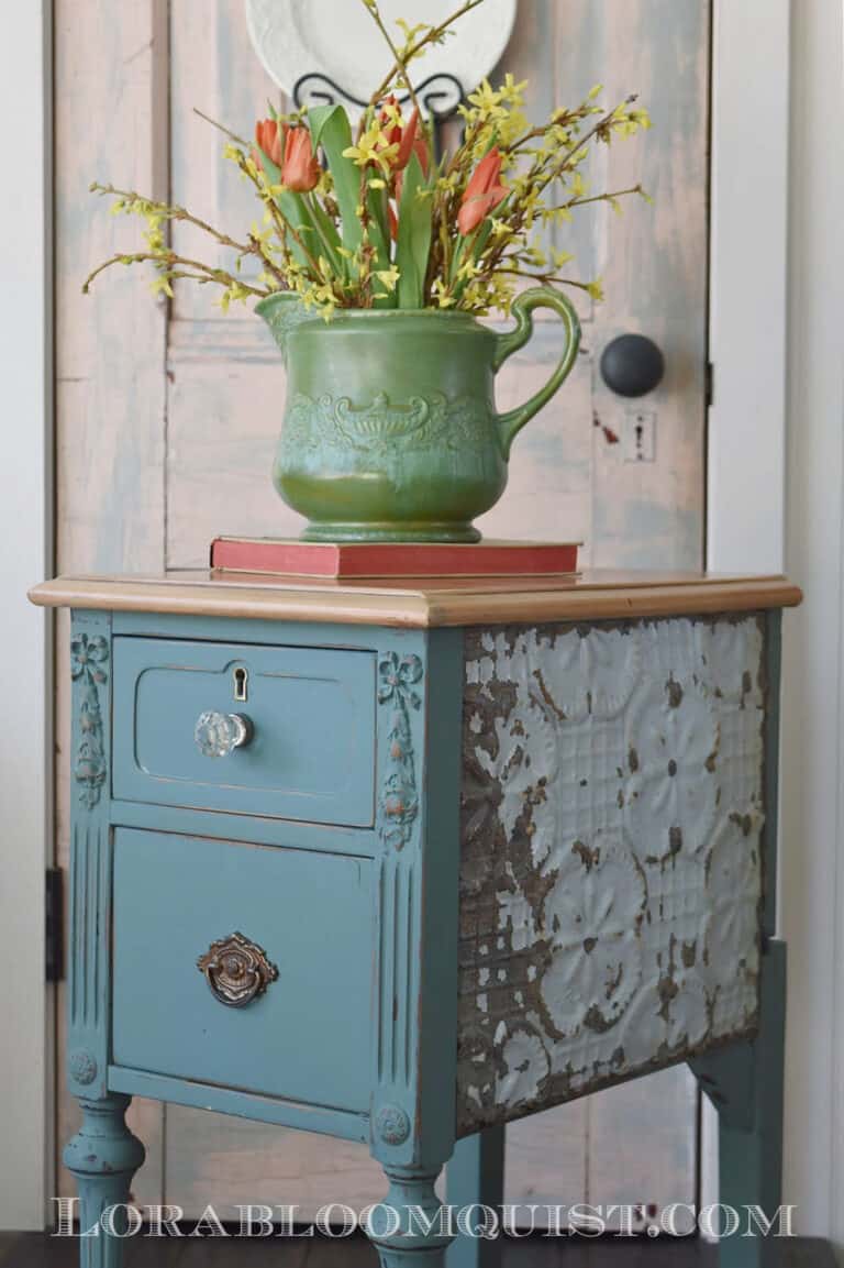 blue side table with green pitcher with flowers sitting on top