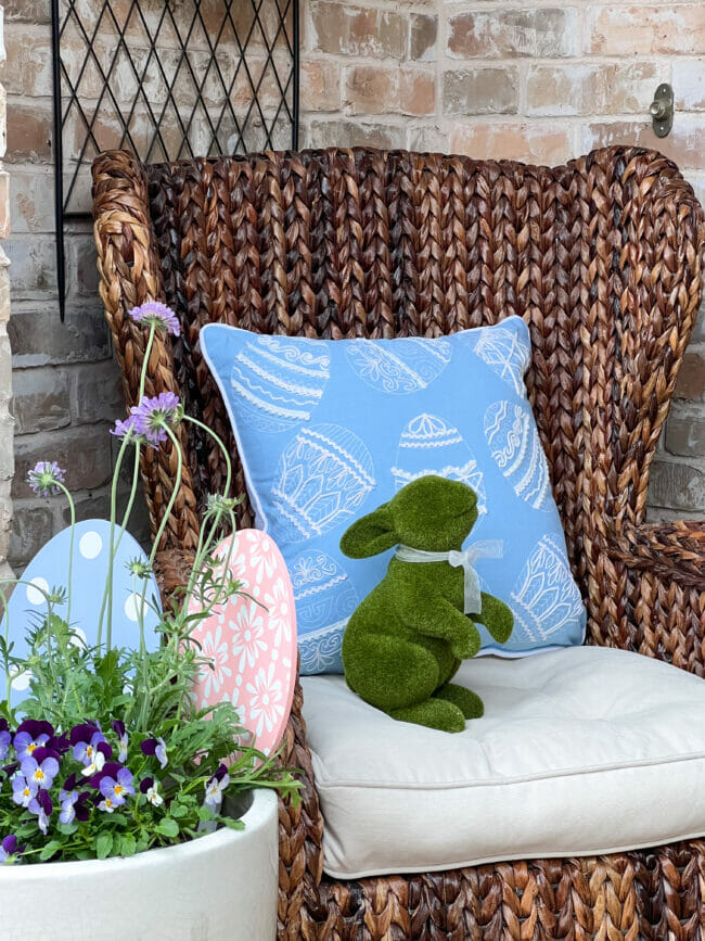 brown rattan chair with blue egg pillow and standing green bunny