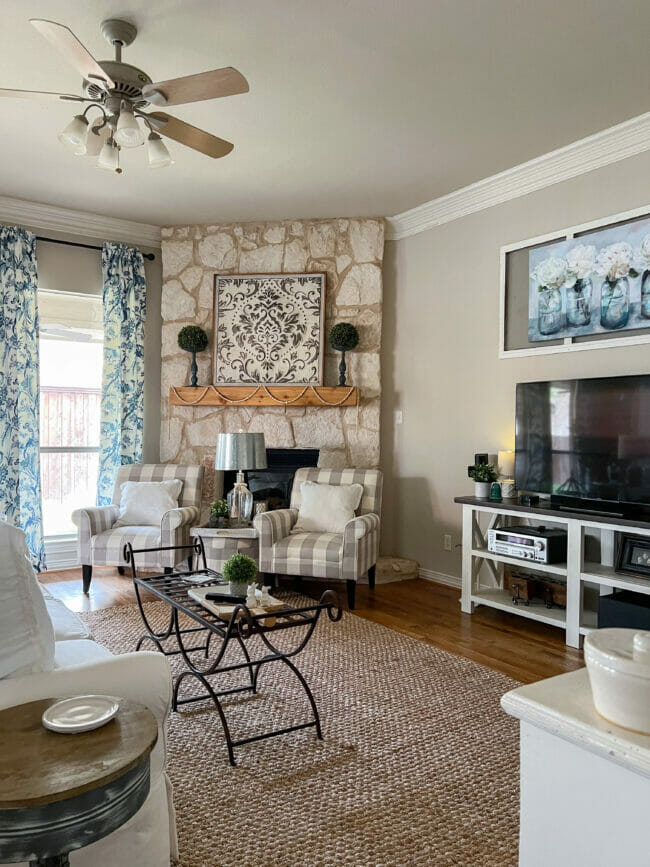 stone fireplace with gray chairs, TV and blue print over TV