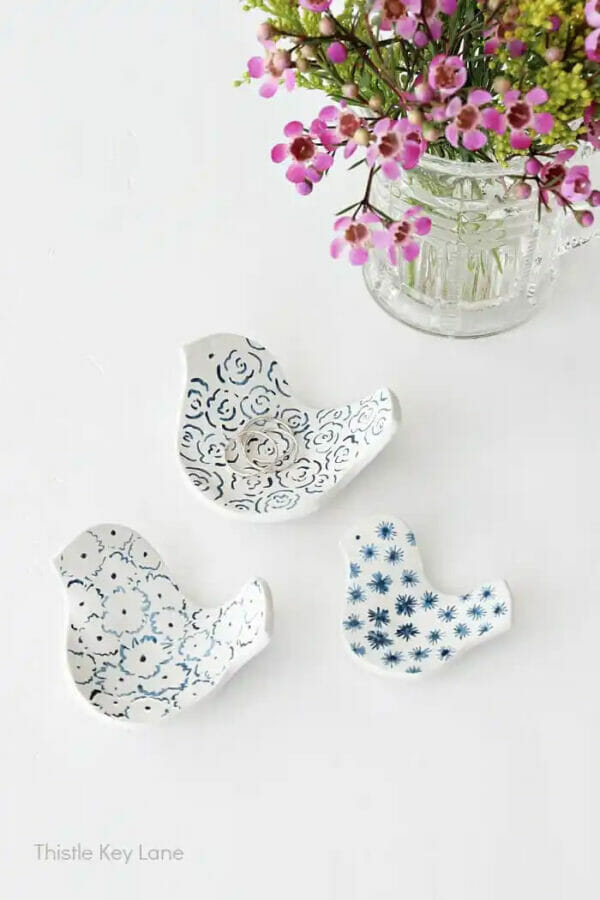 white and blue clay birds dishes with pink flowers in clear vase