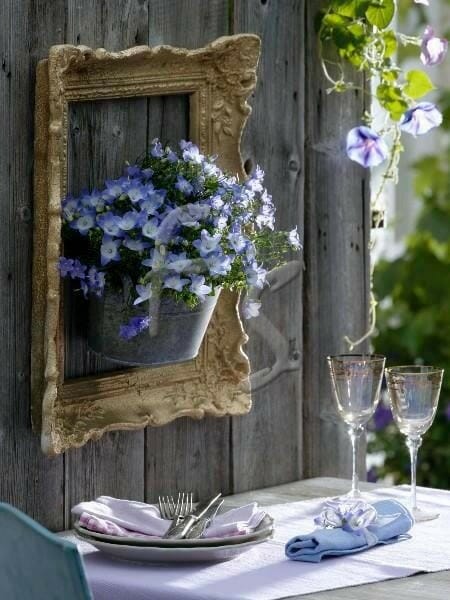 blue flowers hanging in empty frame with table and dishes