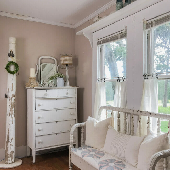 bed bench with quilt, white dresser and column in corner